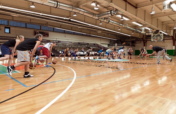 Basketballer dribbeln in einer Halle.